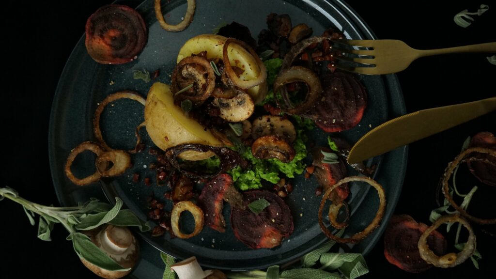Ofenkartoffeln mit gebratenen Champignons und Speck auf Erbsenpüree mit Röstzwiebel sowie Rote-Rüben-Chips