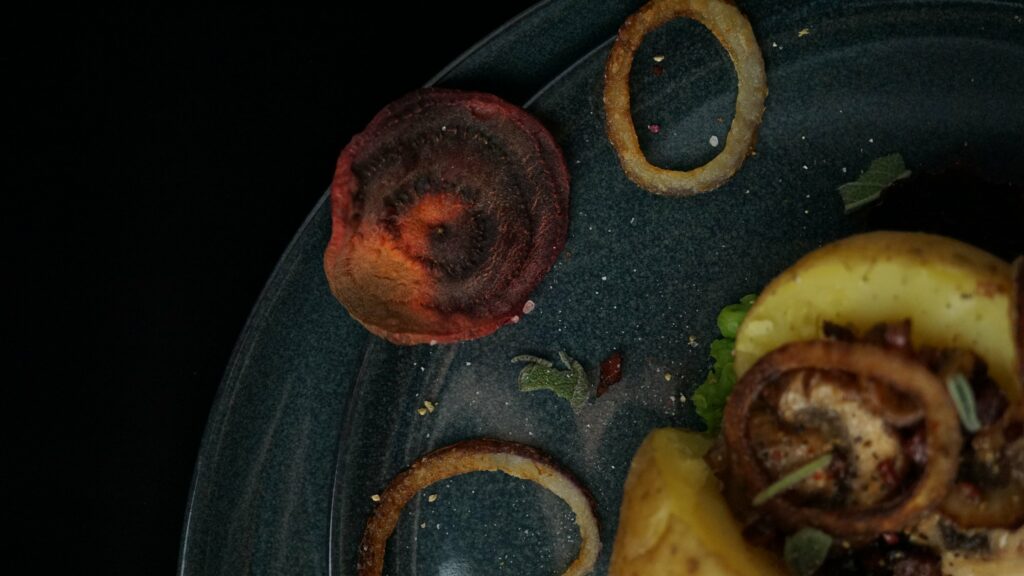 Ofenkartoffeln mit gebratenen Champignons und Speck auf Erbsenpüree mit Röstzwiebel sowie Rote-Rüben-Chips